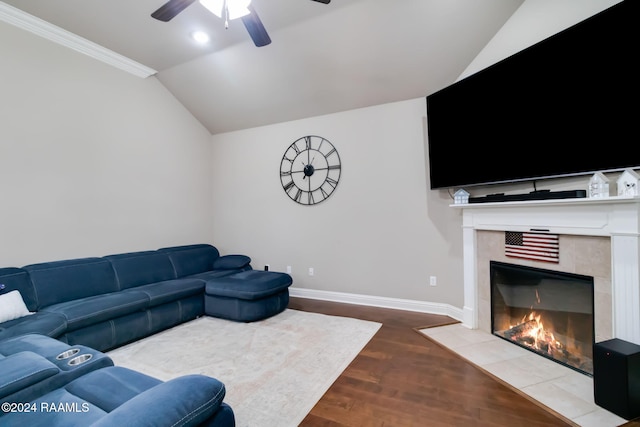 living room with lofted ceiling, ceiling fan, ornamental molding, wood-type flooring, and a tiled fireplace