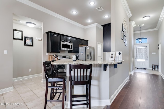 kitchen with a breakfast bar, stainless steel appliances, light hardwood / wood-style flooring, and light stone countertops