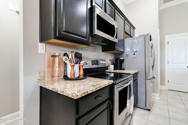 kitchen with light stone countertops, light tile patterned floors, stainless steel appliances, and ornamental molding