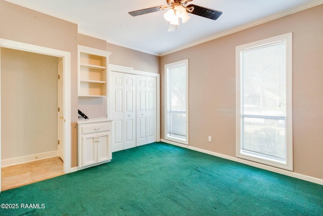 unfurnished bedroom with ceiling fan, dark carpet, and crown molding