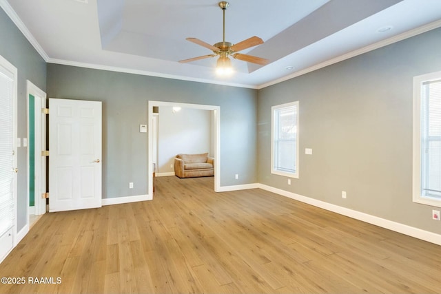 unfurnished bedroom with light wood-type flooring, a tray ceiling, and ornamental molding