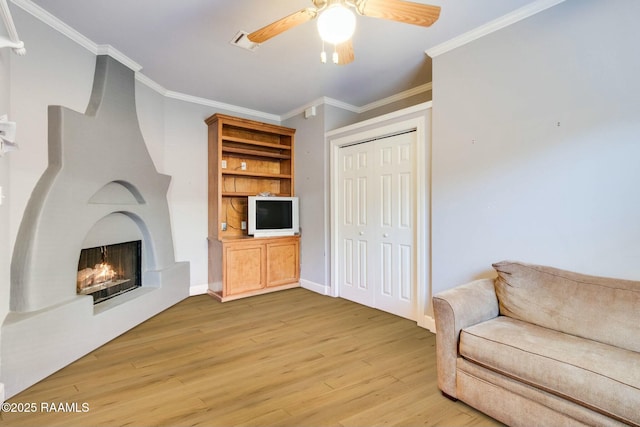 living room featuring crown molding, light hardwood / wood-style flooring, and ceiling fan