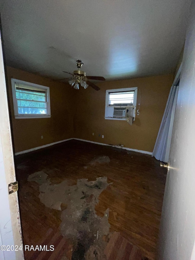 empty room featuring cooling unit, ceiling fan, and dark wood-type flooring