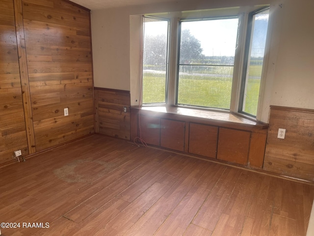 spare room with light hardwood / wood-style flooring and wooden walls