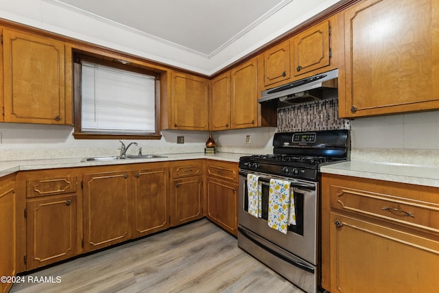 kitchen with light wood-type flooring, stainless steel gas range oven, crown molding, and sink