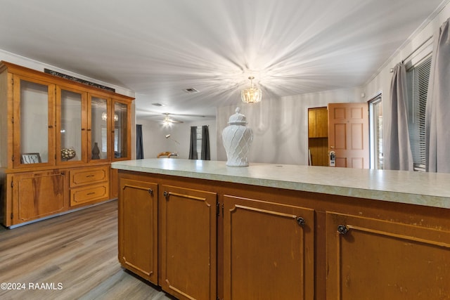 kitchen with light wood-type flooring, decorative light fixtures, ornamental molding, and a notable chandelier