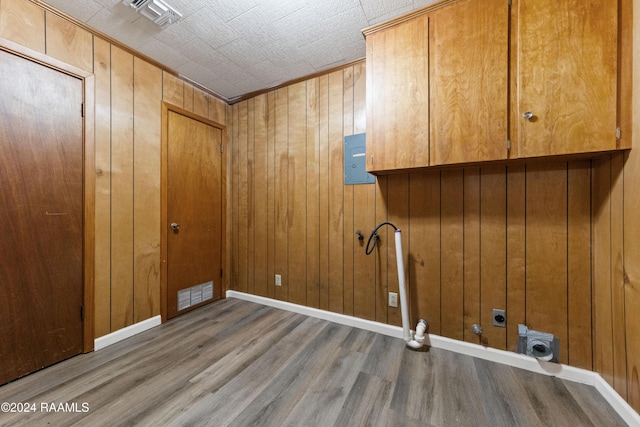 clothes washing area with hardwood / wood-style floors, wood walls, cabinets, electric panel, and hookup for an electric dryer