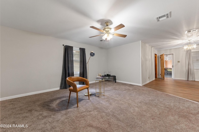 sitting room featuring wood-type flooring and ceiling fan with notable chandelier