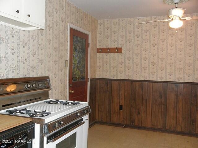 kitchen with dark brown cabinets, wood walls, and white gas range oven