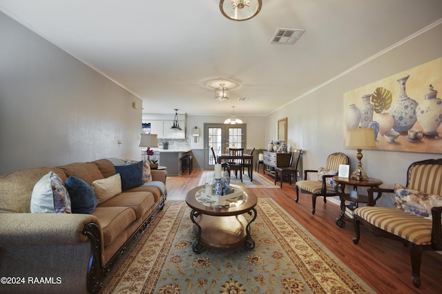 living room featuring hardwood / wood-style flooring, a notable chandelier, ornamental molding, and french doors