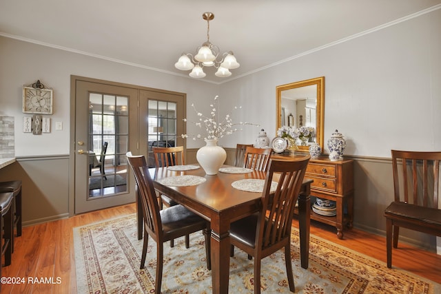 dining room with crown molding, a chandelier, and light wood-type flooring