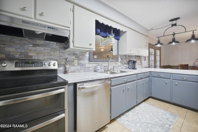 kitchen with appliances with stainless steel finishes, backsplash, hanging light fixtures, and light tile patterned flooring