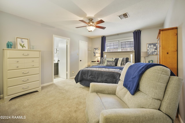 carpeted bedroom featuring a textured ceiling, ensuite bath, and ceiling fan