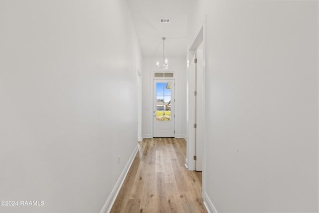 corridor featuring a notable chandelier and light wood-type flooring