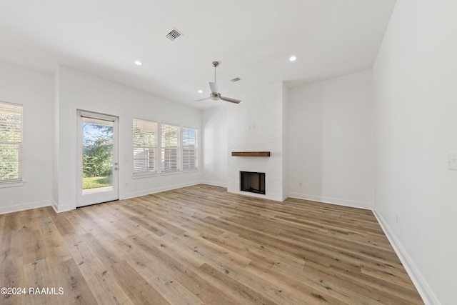 unfurnished living room featuring a brick fireplace, ceiling fan, and light hardwood / wood-style flooring