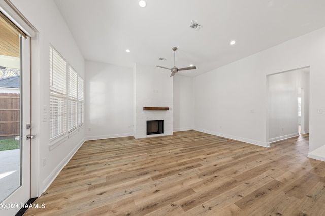 unfurnished living room featuring a fireplace, light hardwood / wood-style flooring, and ceiling fan