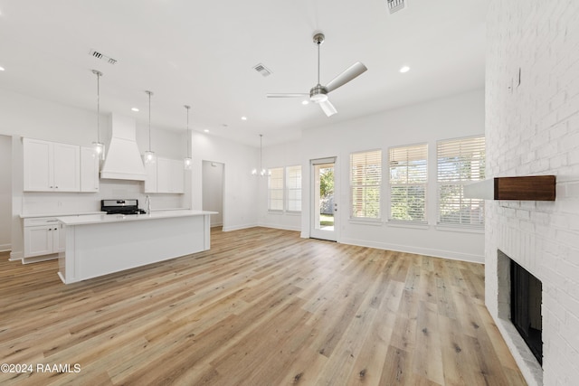 unfurnished living room with ceiling fan, a fireplace, and light wood-type flooring