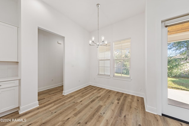 unfurnished dining area featuring light hardwood / wood-style flooring and a chandelier