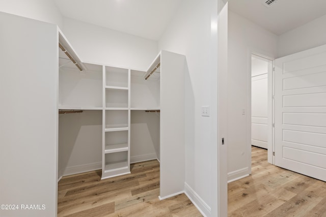 walk in closet with light hardwood / wood-style floors