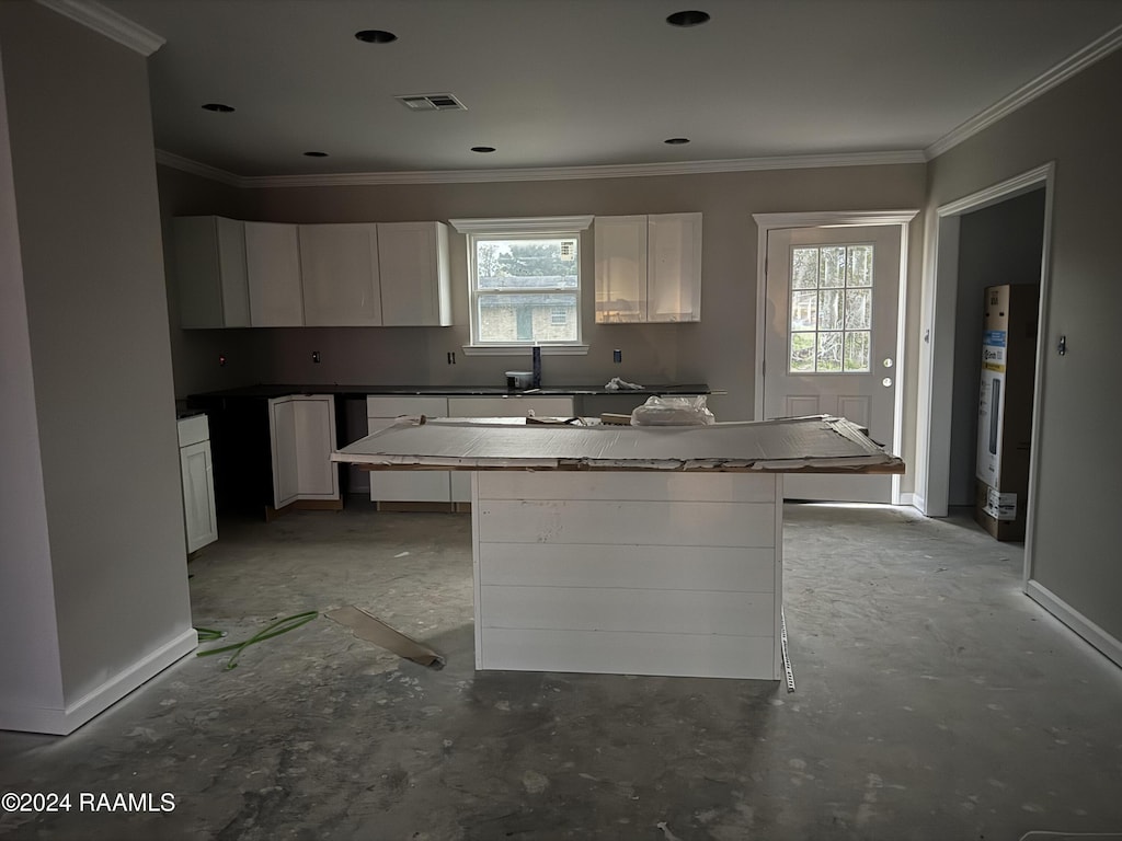 kitchen featuring a kitchen island, crown molding, white cabinetry, and a healthy amount of sunlight