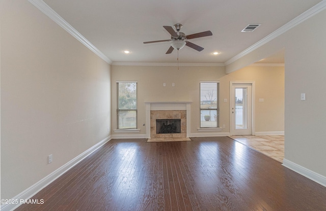 unfurnished living room with crown molding, wood-type flooring, and a tiled fireplace