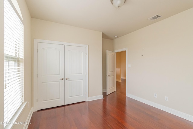 unfurnished bedroom featuring dark hardwood / wood-style flooring and a closet