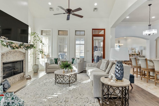 living room with crown molding, a high end fireplace, ceiling fan with notable chandelier, and hardwood / wood-style flooring