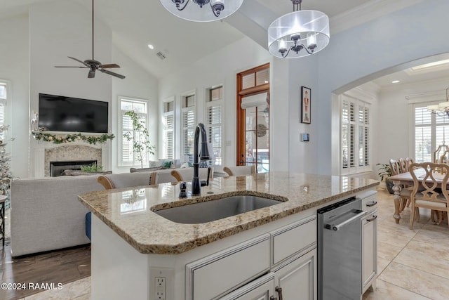 kitchen with light stone countertops, sink, high vaulted ceiling, an island with sink, and pendant lighting