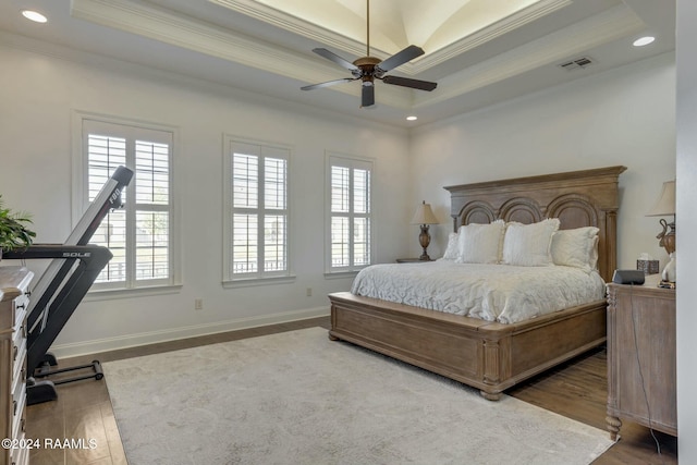 bedroom featuring dark hardwood / wood-style floors, a raised ceiling, ceiling fan, and crown molding