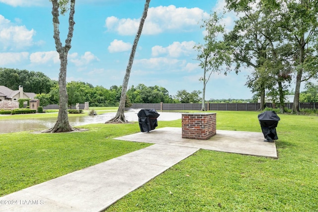 view of community with a lawn, a patio area, and a water view