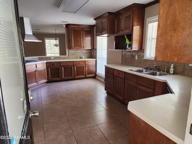 kitchen featuring sink, kitchen peninsula, pendant lighting, extractor fan, and decorative backsplash