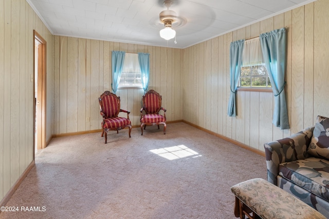 sitting room with ceiling fan, light carpet, and wooden walls