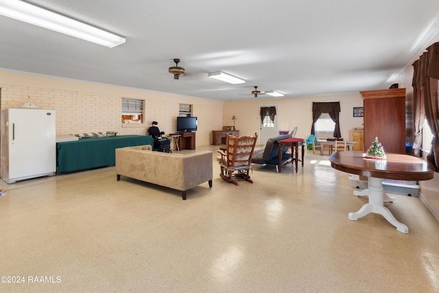 living room with ceiling fan and brick wall