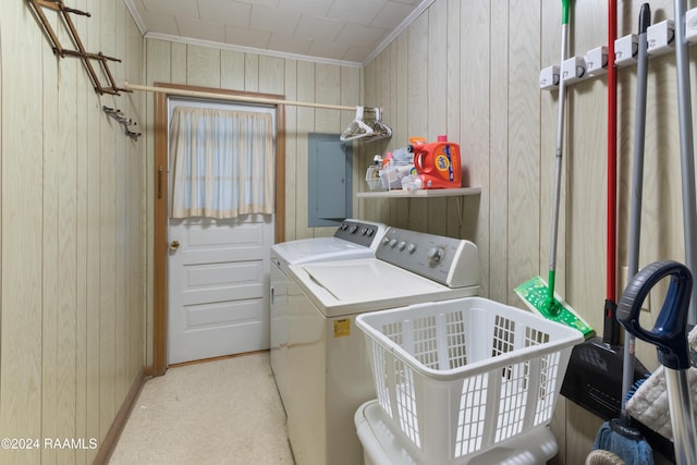 clothes washing area featuring wood walls, light colored carpet, separate washer and dryer, and electric panel