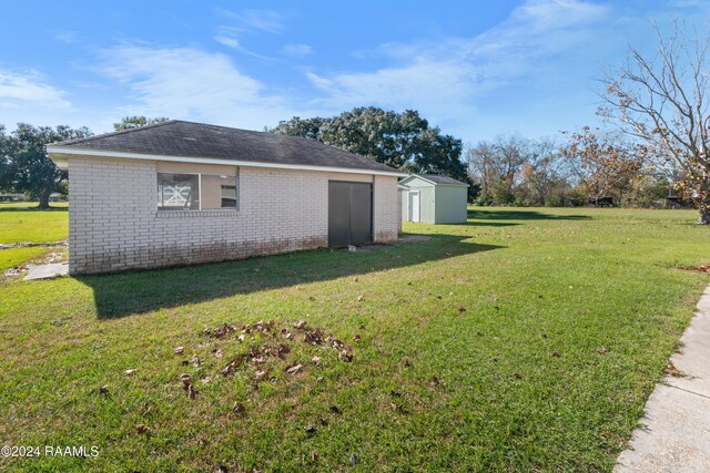 view of side of property with a storage shed and a yard