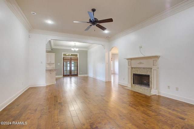 unfurnished living room with a fireplace, wood-type flooring, ceiling fan with notable chandelier, and ornamental molding