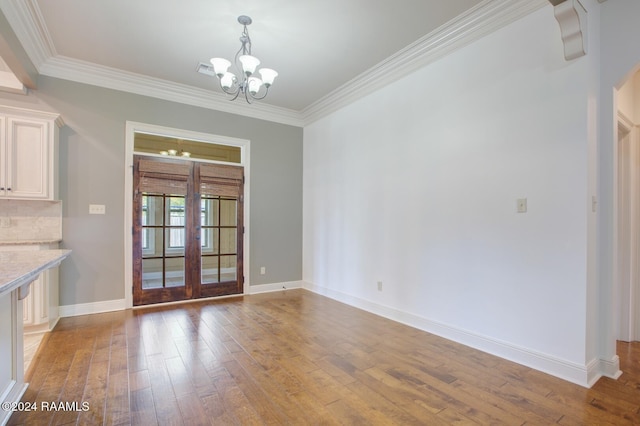 unfurnished dining area featuring french doors, wood-type flooring, ornamental molding, and a chandelier