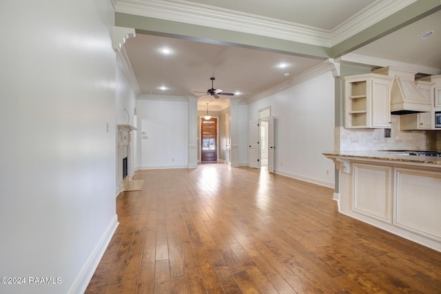 unfurnished living room featuring ceiling fan, ornamental molding, and light wood-type flooring