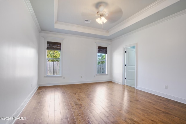 spare room featuring a tray ceiling, crown molding, ceiling fan, and wood-type flooring