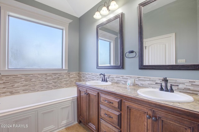 bathroom with tasteful backsplash, a tub, vanity, and vaulted ceiling