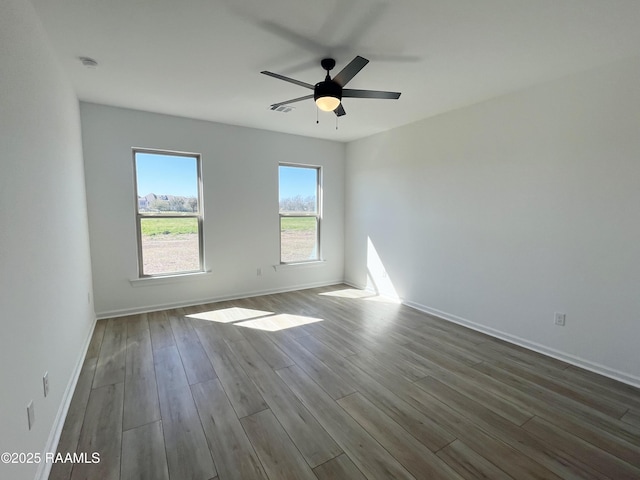 empty room with visible vents, baseboards, ceiling fan, and dark wood-type flooring