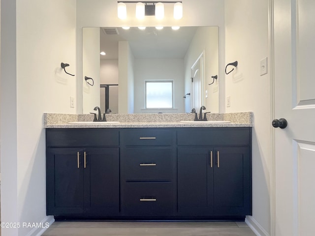 bathroom with double vanity, a sink, visible vents, and baseboards