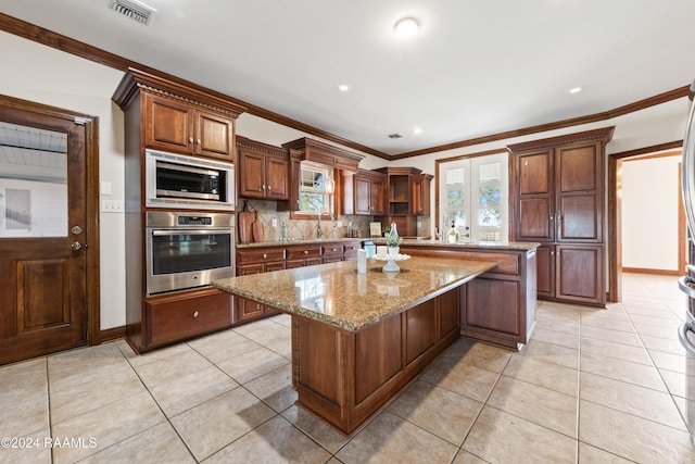 kitchen with decorative backsplash, appliances with stainless steel finishes, ornamental molding, light tile patterned floors, and a kitchen island