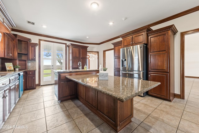 kitchen with light tile patterned flooring, a kitchen island, ornamental molding, and light stone counters