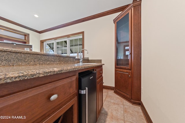 kitchen featuring stainless steel refrigerator, sink, crown molding, dark stone counters, and light tile patterned floors