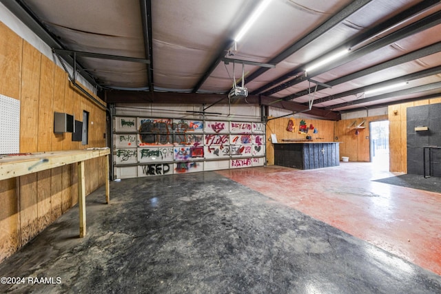 garage with a workshop area, wood walls, and a garage door opener