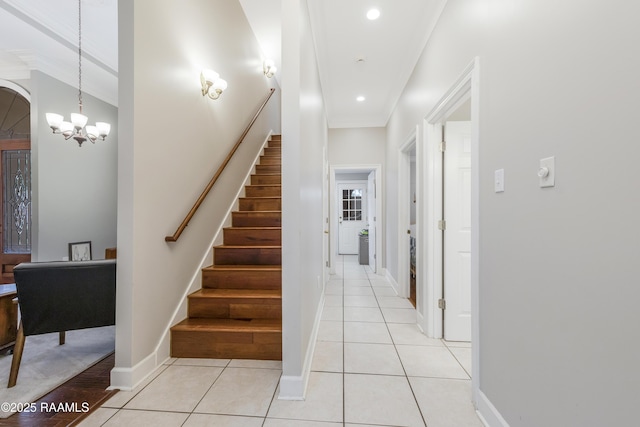 stairs with an inviting chandelier, ornamental molding, and tile patterned flooring