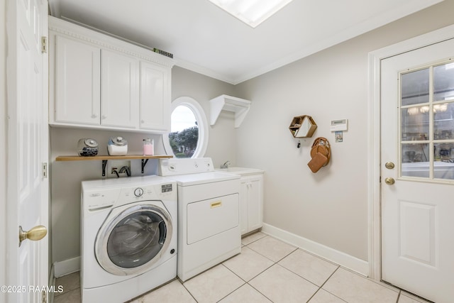 laundry room featuring cabinets, light tile patterned flooring, washing machine and clothes dryer, and crown molding