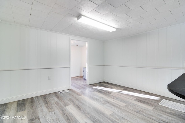 unfurnished room featuring wood walls and light wood-type flooring