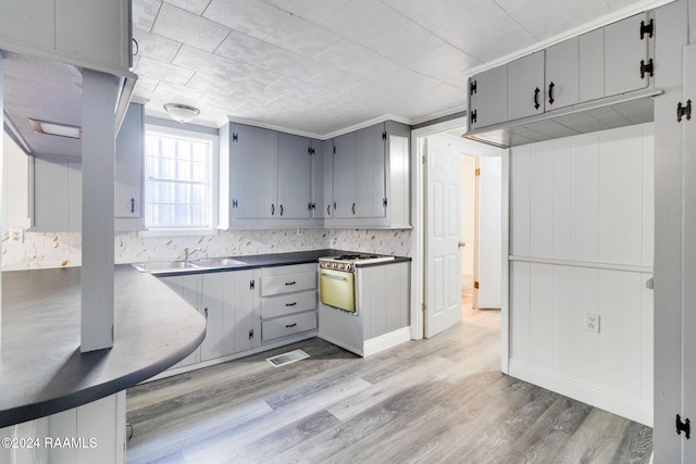 kitchen with decorative backsplash, gray cabinetry, crown molding, sink, and light hardwood / wood-style floors